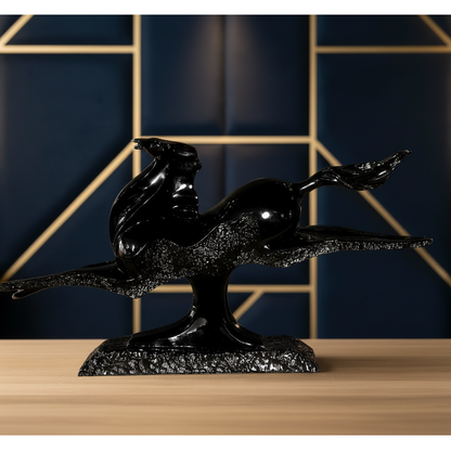 Black decorative sculpture on a wooden surface with a geometric patterned wall in the background