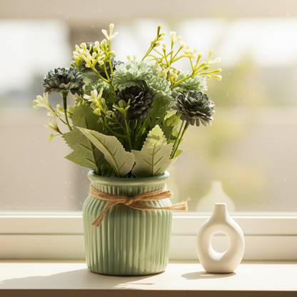 Small potted plant with greenery in a green pot on a plain background
