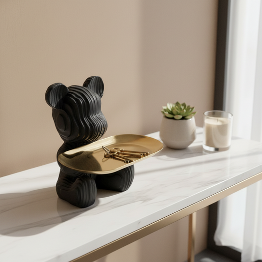 Black bear-shaped object with a gold plate on a white surface