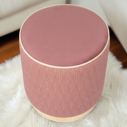 Round pink ottoman with geometric pattern on a white rug