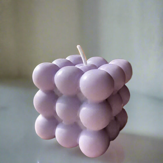 Cube-shaped candle with bubble design on a wooden surface