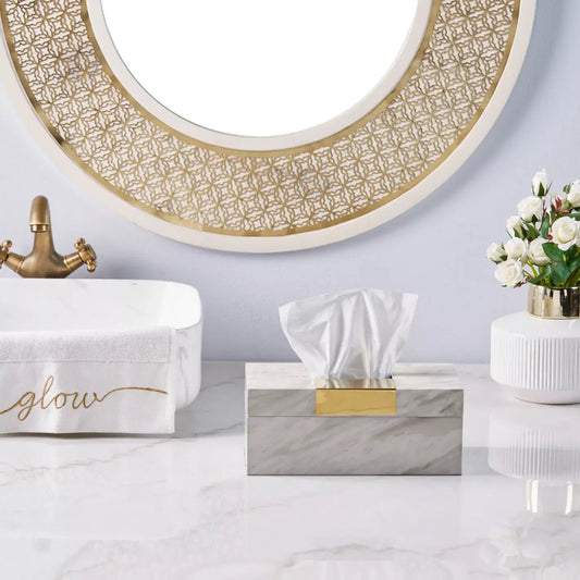 Bathroom setting with tissue box, towel, and decorative mirror.