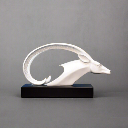 White decorative animal sculpture on a wooden surface with abstract art in the background