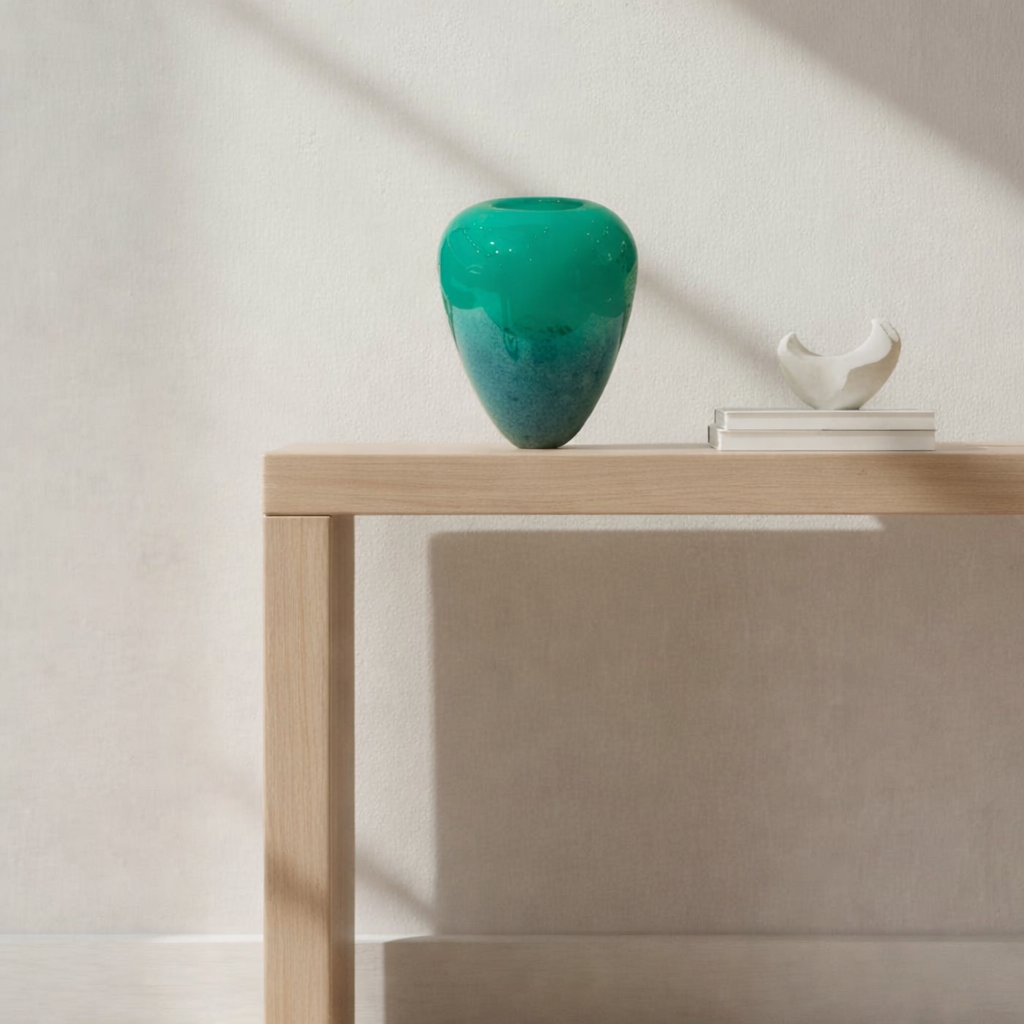 Green vase on a wooden table with a minimal background